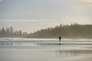 Man walking with surfboard through the mist Long Beach Pacific Rim National Park
