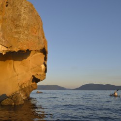 Sea kayaking under sculpted sandstone cliffs