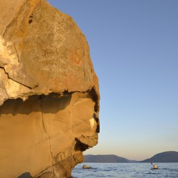 Sea kayaking under sculpted sandstone cliffs