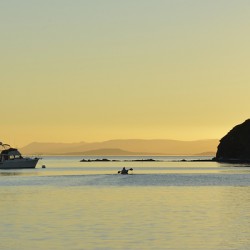 Kayaker and motor boat at anchor in Fox Cove. Sucia Island